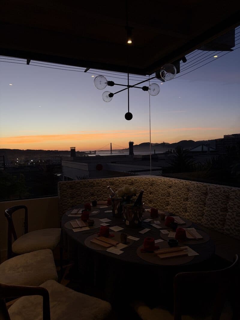 A dinner table set for guests at sunset overlooking San Francisco